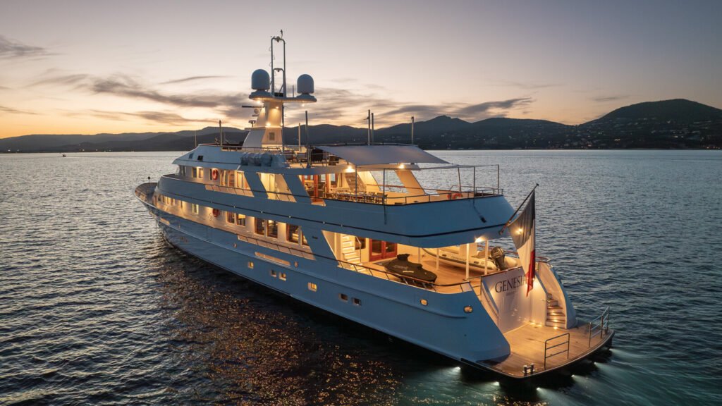 Genesia at anchor at dusk, deck lights lit