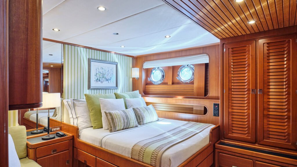 Guest stateroom with twin portholes and green striped decor