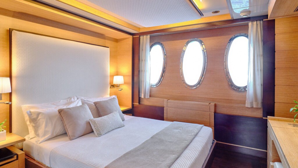 Master stateroom with queen bed and triple portholes
