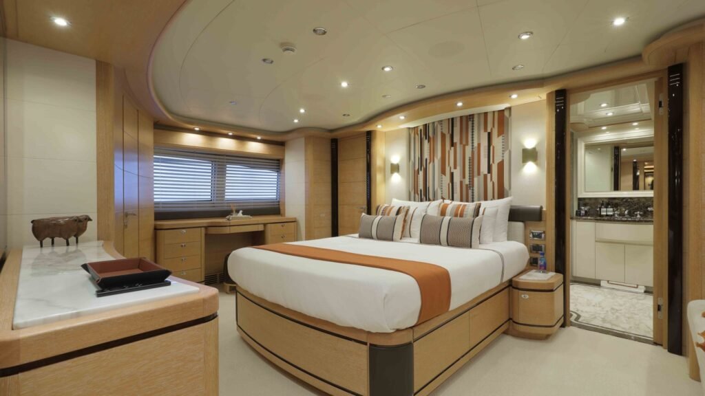 Master stateroom with orange accent bedding and en-suite door