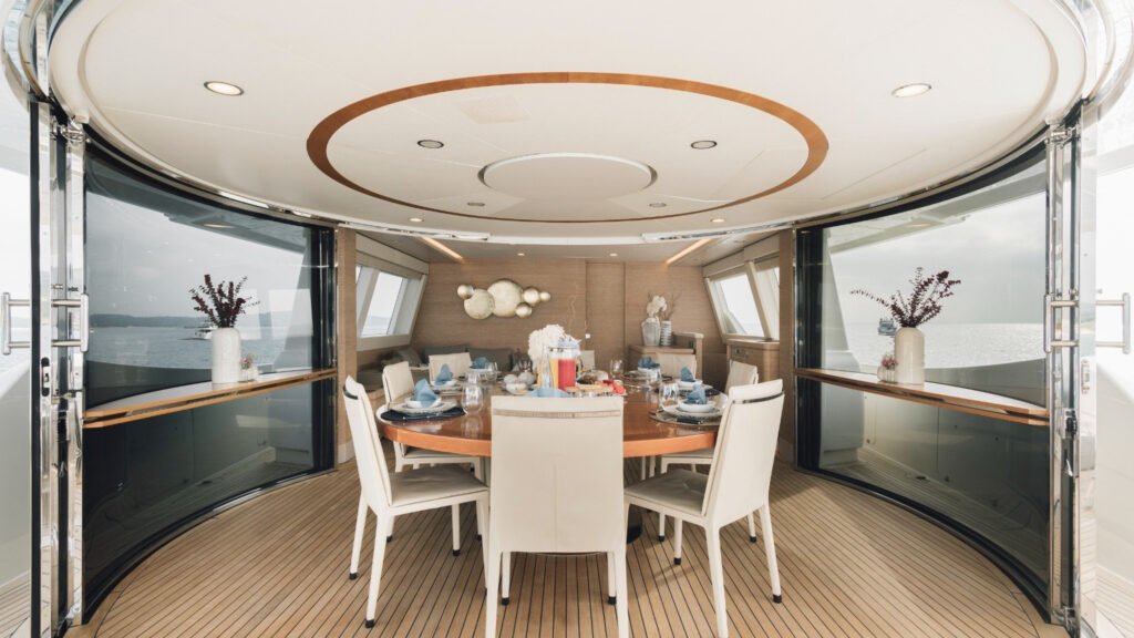 Main salon with curved glass windows and dining table aboard motor yacht Centurion