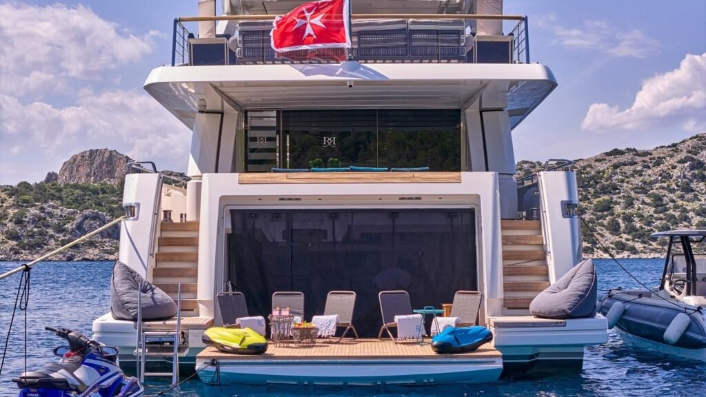 Open transom garage and swim platform aboard RIANA II with loungers and tender