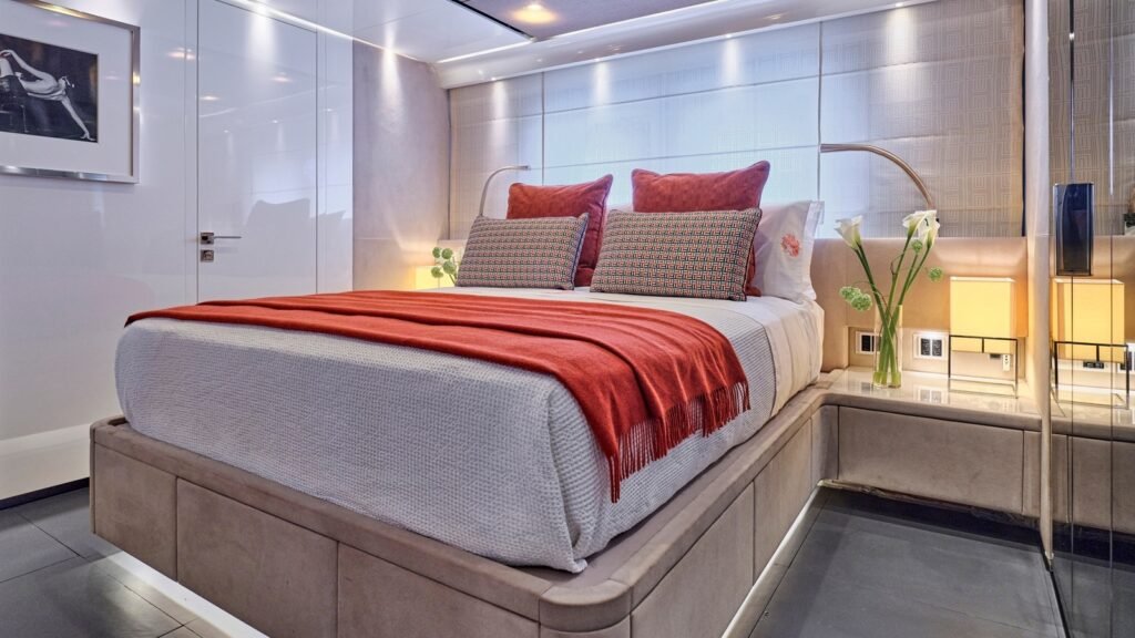 Guest double cabin aboard RIANA II in white lacquer with a scarlet throw