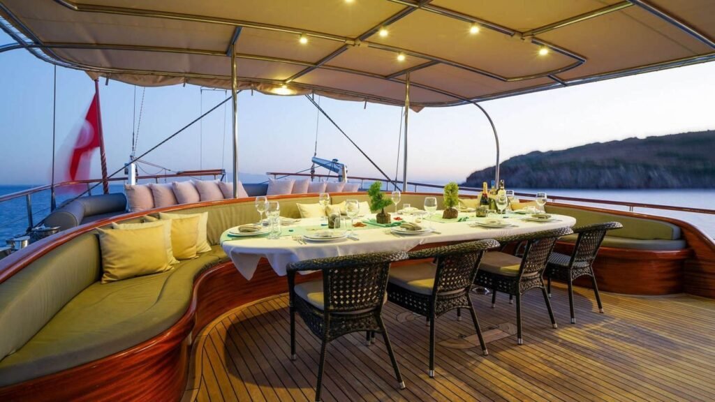 Al fresco dining table on the aft deck with dramatic coastal backdrop