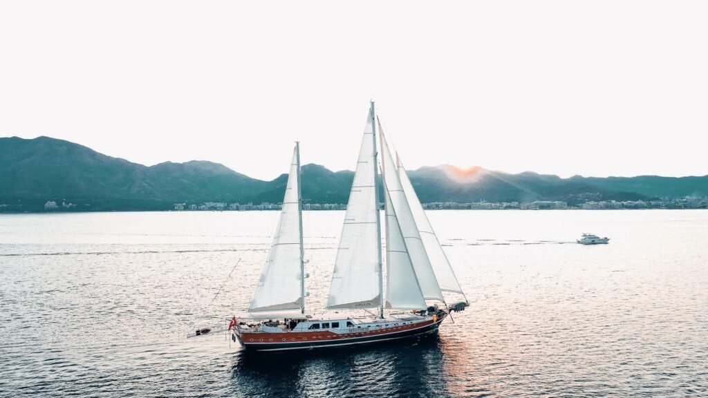 La Bella Vita under sail at sunset with masts and rigging silhouetted